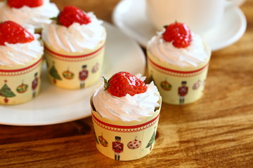 Cupcake of white cream and strawberry on the table with tea cup