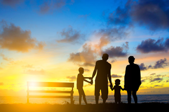 Silhouette family mother, father and young son holding hands, ta