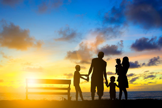 Silhouette family mother, father and young son holding hands, ta
