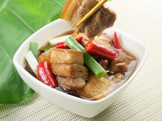 Cane fragrant braised pork with chili and onion in white pot on