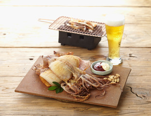 Dried squid with sauces, beer and hot grill on wooden background