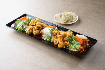 Vile chicken with sliced onion, cucumber and herbs on black plat