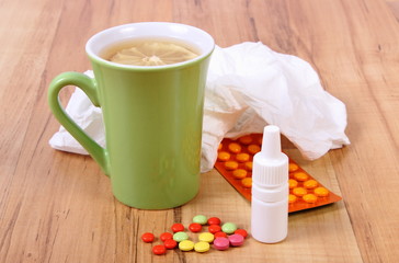 Pills and nose drops for colds, handkerchiefs and hot tea with lemon