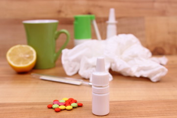 Fototapeta na wymiar Pills and nose drops for colds, used handkerchiefs and hot tea with lemon