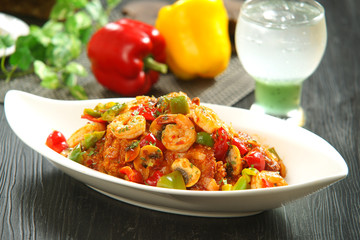 Fried shrimp with mushroom, chili on wooden table with glass of