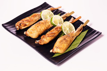 Roasted pepper chicken wings with lemon on black plate