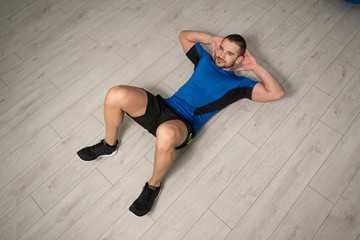 Young Man Performing Abdominal Exercise On Floor