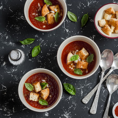 Three bowls of gazpacho soup on a dark background. Healthy vegetarian food. Top view
