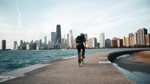 Cyclist rides at seaside with skyscrapers on the background