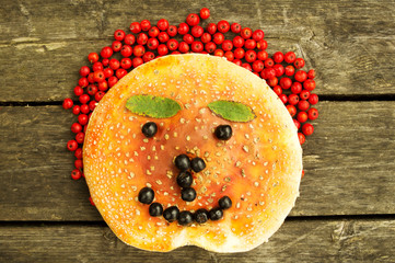 Funny face made from  mushrooms, berries and leaves .On the wooden background