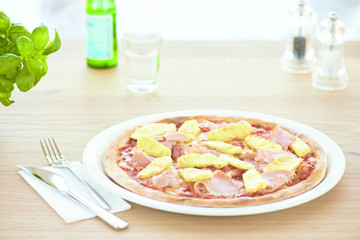 Pineapple pizza on white plate in the restaurant