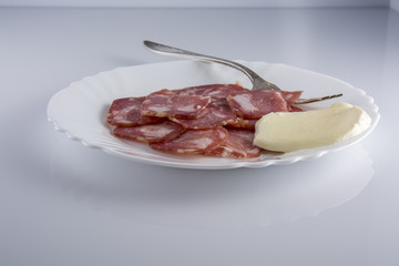 Мясная нарезка с моцареллой на оранжевой тарелке на светлом фоне