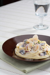 Bonggolre cream sauce pasta with clams on black plate with glass
