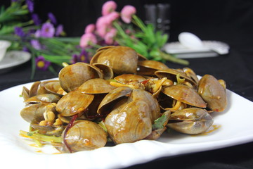 Spicy clams with vegetable on white plate in black background