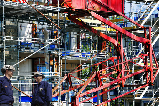 two construction workers with giant scaffoldings in background