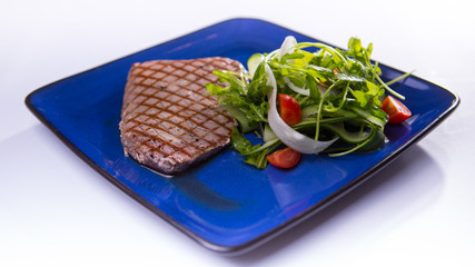 Tuna steak with meat dressing shouts on blue chinese plate on wh