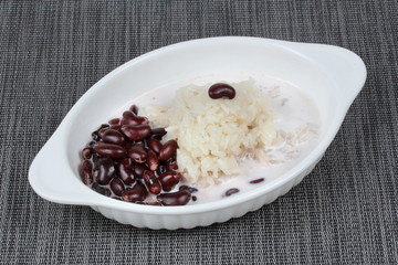 Black bean and sticky rice in sweet coconut cream topped coconut milk on black. Side view.