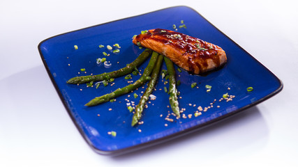 Salmon teriyaki with asparagus in blue chinese plate on white ba