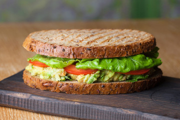 Sandwich with grilled vegetables on black wooden tray