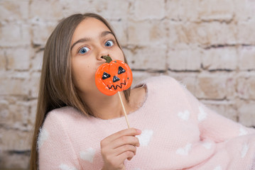 halloween candy. Girl teenager on Halloween. Cheerful girl with a sweet, beautiful teenager girl holding a candy on stick. Girl with long hair in a Halloween theme
