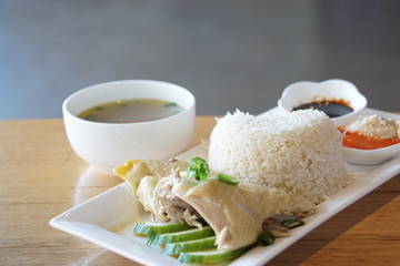 Chicken rice with sliced cucumber, bowl of soup, soyal and chili