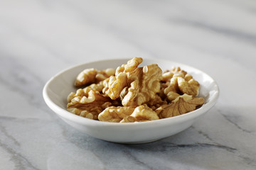 Dried walnuts in white plate on Marble Surface