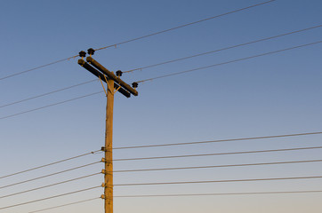 Power line on wooden poles at sunset