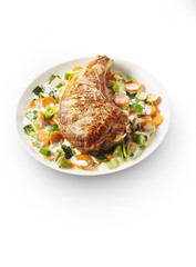 Veal chop with vegetable cream on white plate in restaurant