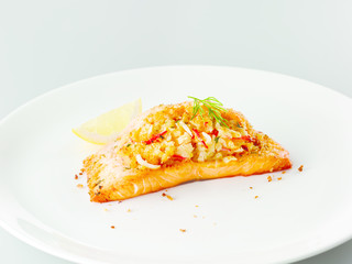 Fried stuffed salmon with lemon and herbs on white plate in rest