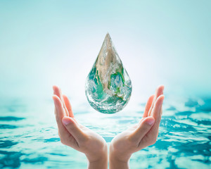 Green globe in woman human hand, drinking water  on blur natural blue ocean background: World...