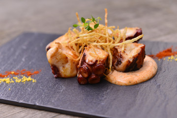 Hot Tapas of fried octopus with sauce on black rock plate