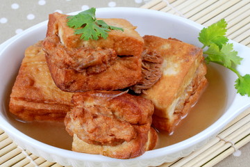 Close up of gold bar soup as fried tofu wrap minced pork in soup and coriander on bamboo. Selective focus