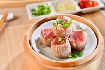 Dishes of ham dumplings on bamboo tray in asian restaurant