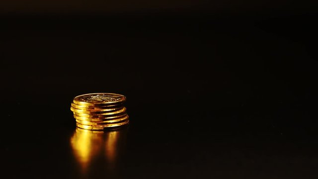 Gold coins on a black background. A stack of coins on a black background. Pile of coins on the left