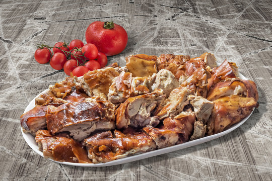 Plateful of Spit Roasted Pork Slices With Bunch of Tomato On Old Wooden Background