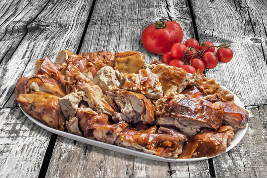 Plateful of Spit Roasted Pork Slices With Bunch of Tomato On Old Wooden Background