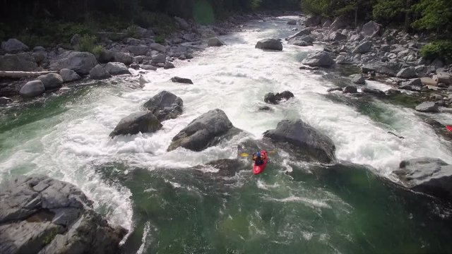 Aerial Shot Following Young Woman in Kayak Down River with White Water Rapids