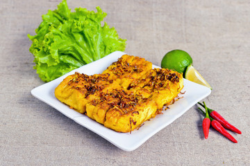 Fried tofu with lemongrass on white plate with lettuce, chili an