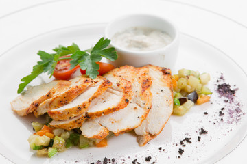 Roasted chicken breast with ratatouille and herbs on white plate