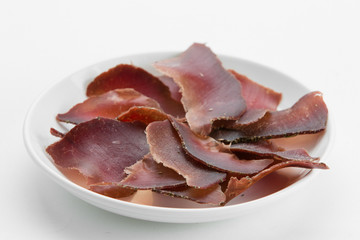 Sliced dried beef meat jerky on white plate