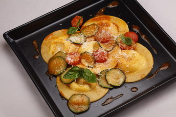 Ravioli stuffed with pumpkin and amaretti wine sauce on black pl