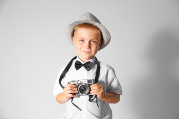 Little boy with vintage camera on grey background