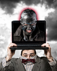 Timid man holds the laptop showing his aggressive virtual personality