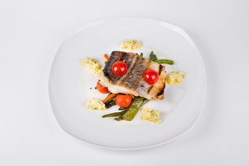 Fillet of fried cod with vegetables on white plate