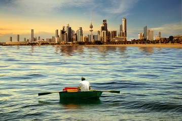 A man rowing boat on the sea of kuwait city during sunset