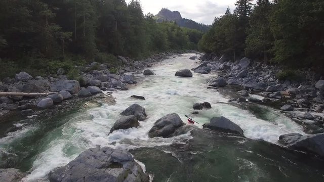 Aerial Shot of Kayaker Padding Down Raging River in Mountain Forest