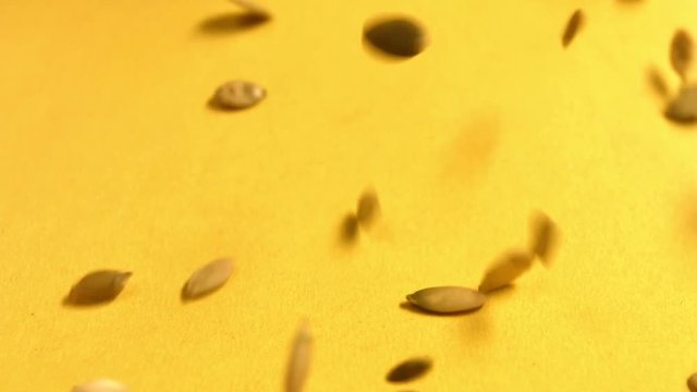Shelled pumpkin seeds on a yellow background. Slow motion. Close-up. Horizontal pan. 2 Shots