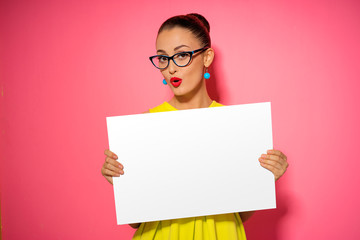 Your text here. Pretty young excited woman holding empty blank board. Colorful studio portrait with...