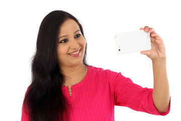 Happy young woman taking a selfie against white background