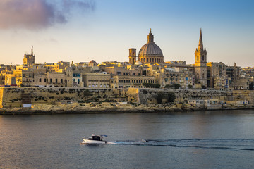 Fototapeta na wymiar Valletta, Malta - St.Paul's Cathedral and the ancient city of Valletta with motorboat at sunrise